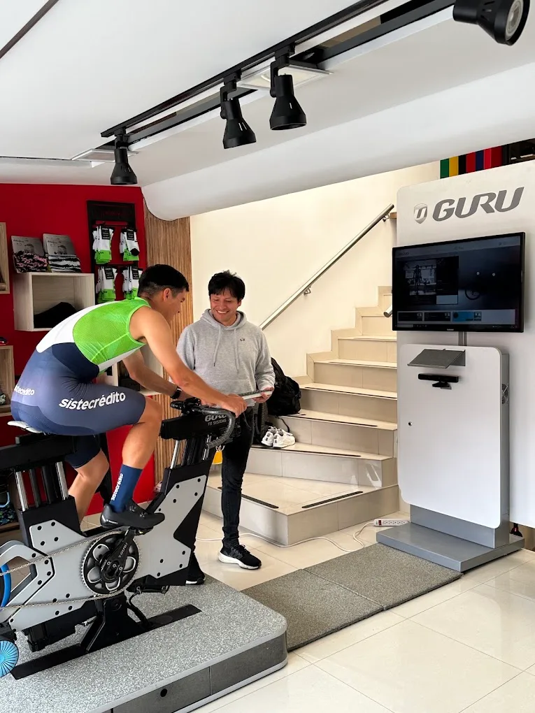 Juan Diego Guerrero, ciclista del Team Sistecrédito, pedalea en el simulador GURU mientras Edwin Castiblanco sigue su estudio BIKEFINDER en la tableta