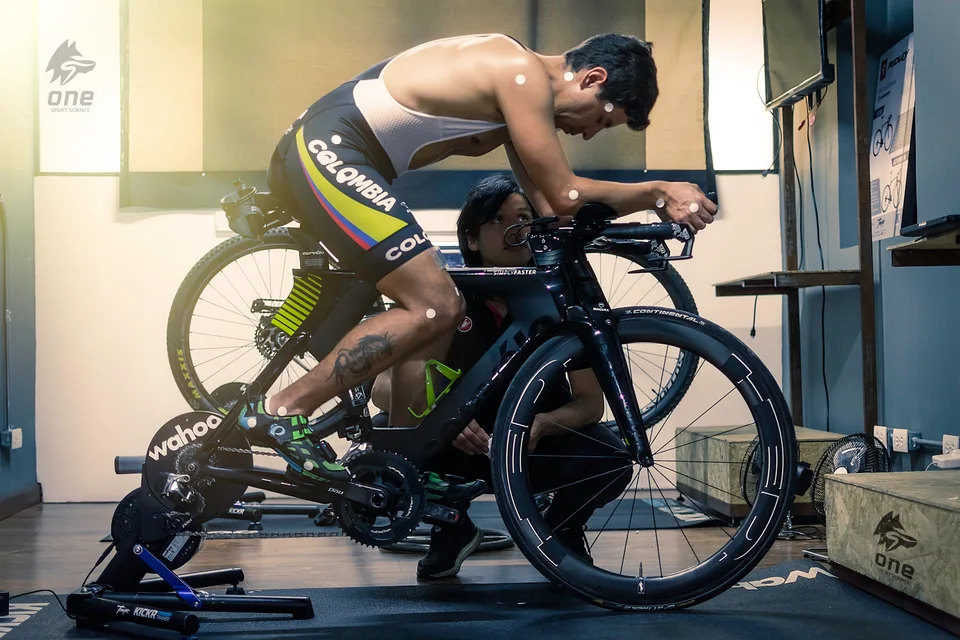 Triatleta con marcadores sobre la bicicleta de contrarreloj mientras se revisa la posición desde el suelo