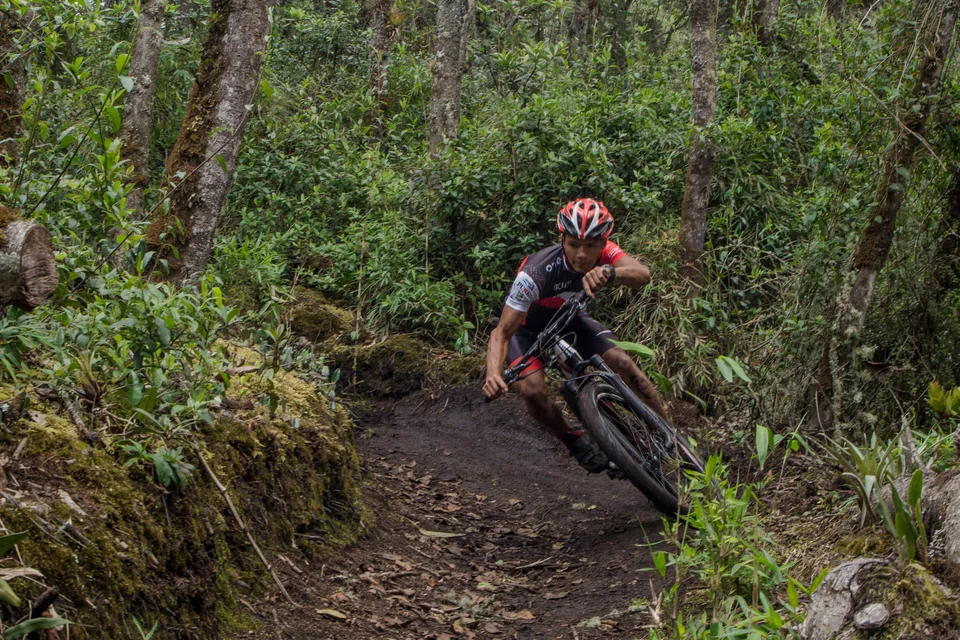 Ciclista de montaña de pie sobre los pedales trazando una curva en sendero