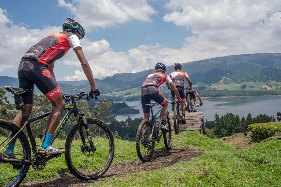 Ciclistas de montaña encadenando un paso de madera en un sendero cerca de Bogotá