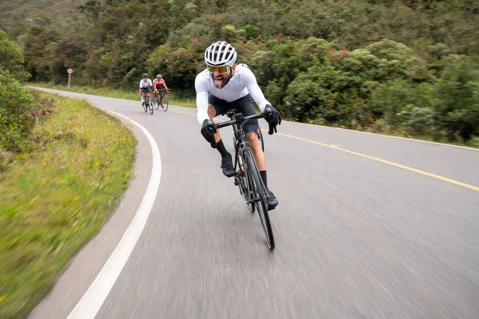 Ciclista inclinando la bicicleta en una curva de descenso en carretera