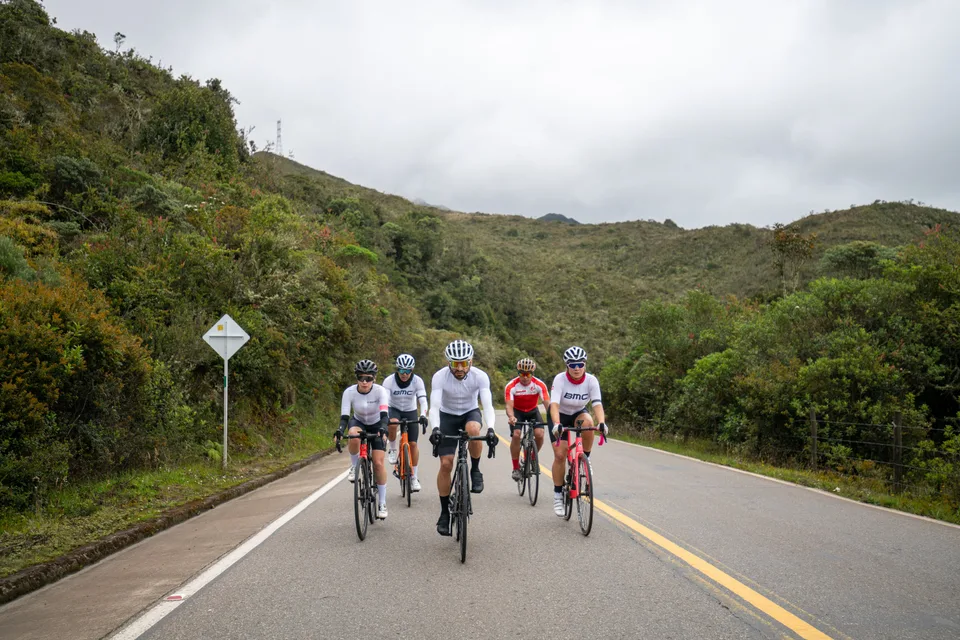 Grupo de ciclistas de ONE rodando junto en una carretera de montaña