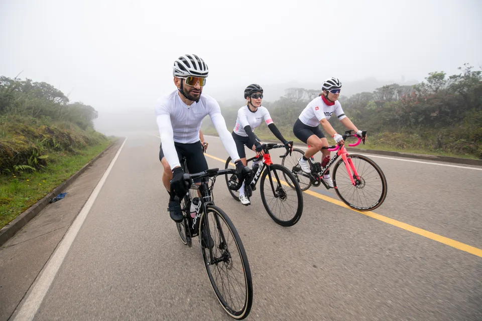 Grupo de ciclistas de ONE rodando entre la niebla en una carretera de montaña