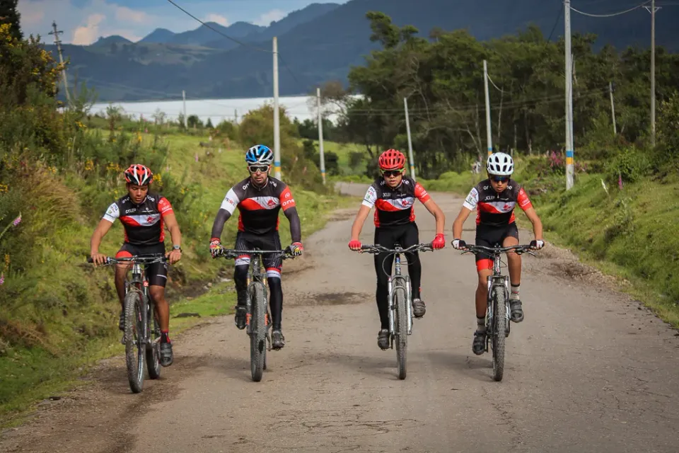 Cuatro ciclistas de montaña de ONE rodando juntos por un camino destapado