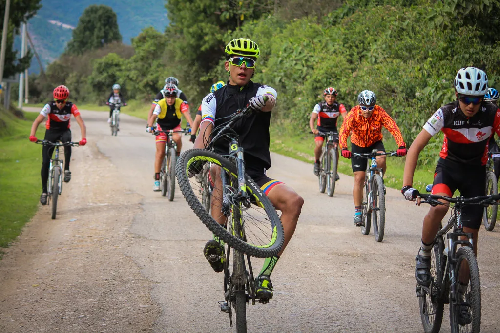 Grupo de ciclistas de montaña de ONE en un camino destapado, uno de ellos levantando la rueda delantera
