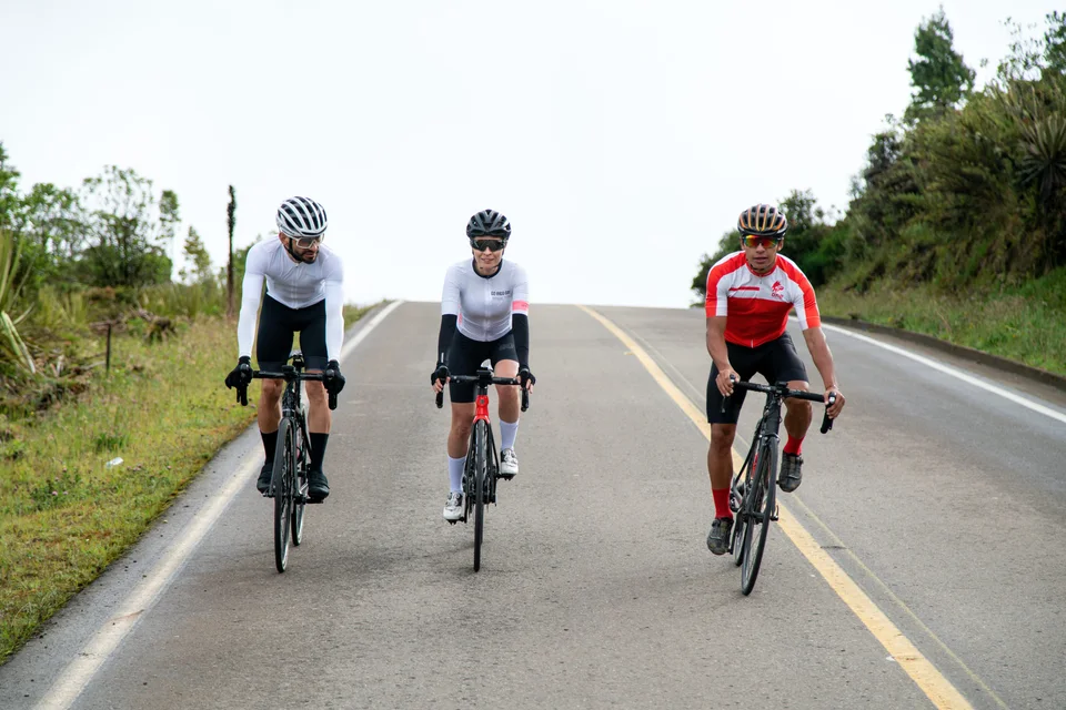 Grupo de ciclistas entrenando juntos en una carretera de montaña con ONE